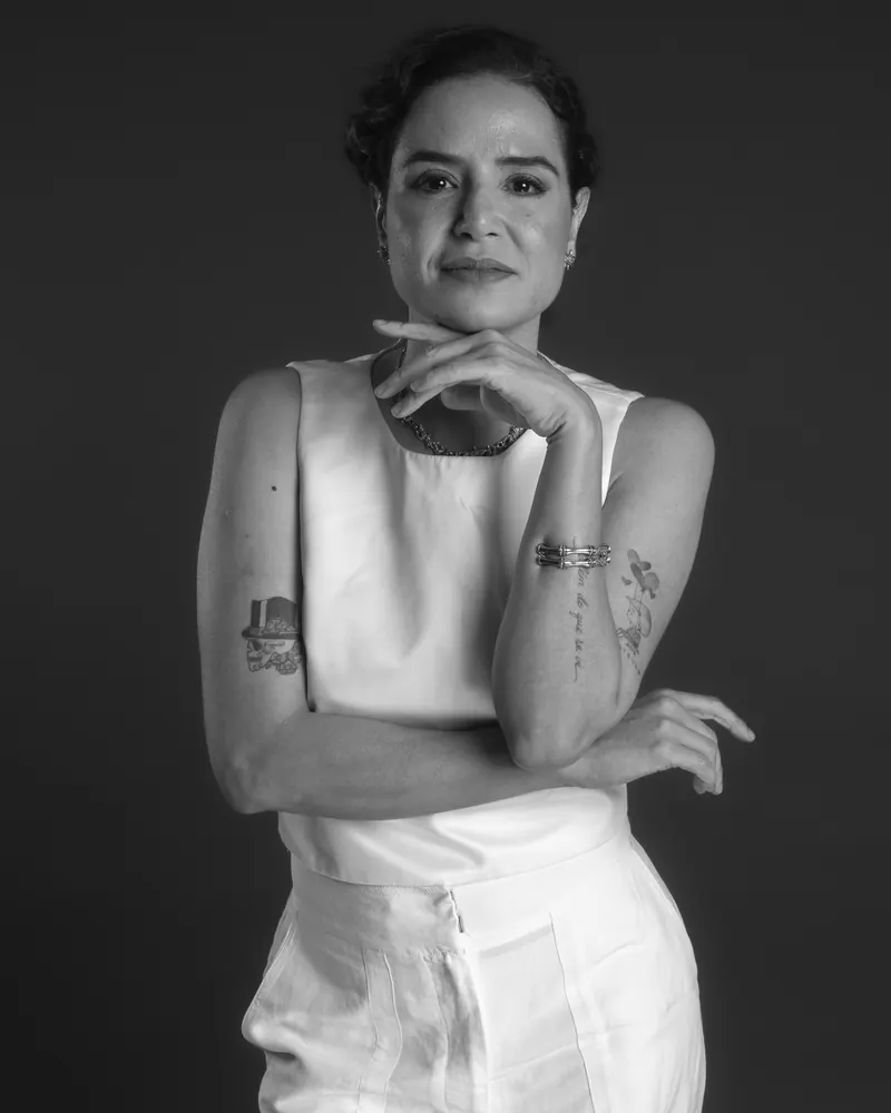 Retrato em preto e branco da Dra. Anna Carolina Rocha, com a mão apoiada no queixo